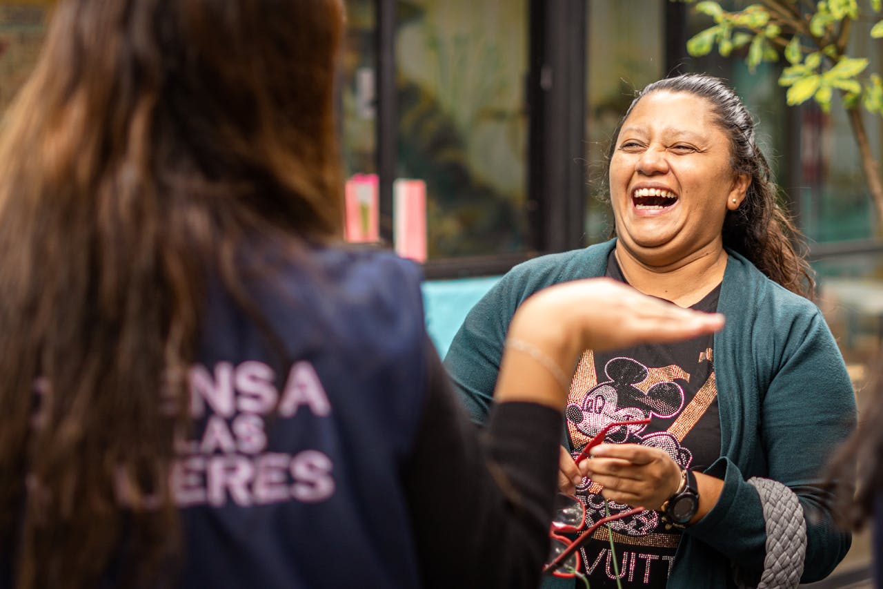 Two women sharing a moment of laughter outdoors in Ciudad de México, showcasing happiness and friendship.