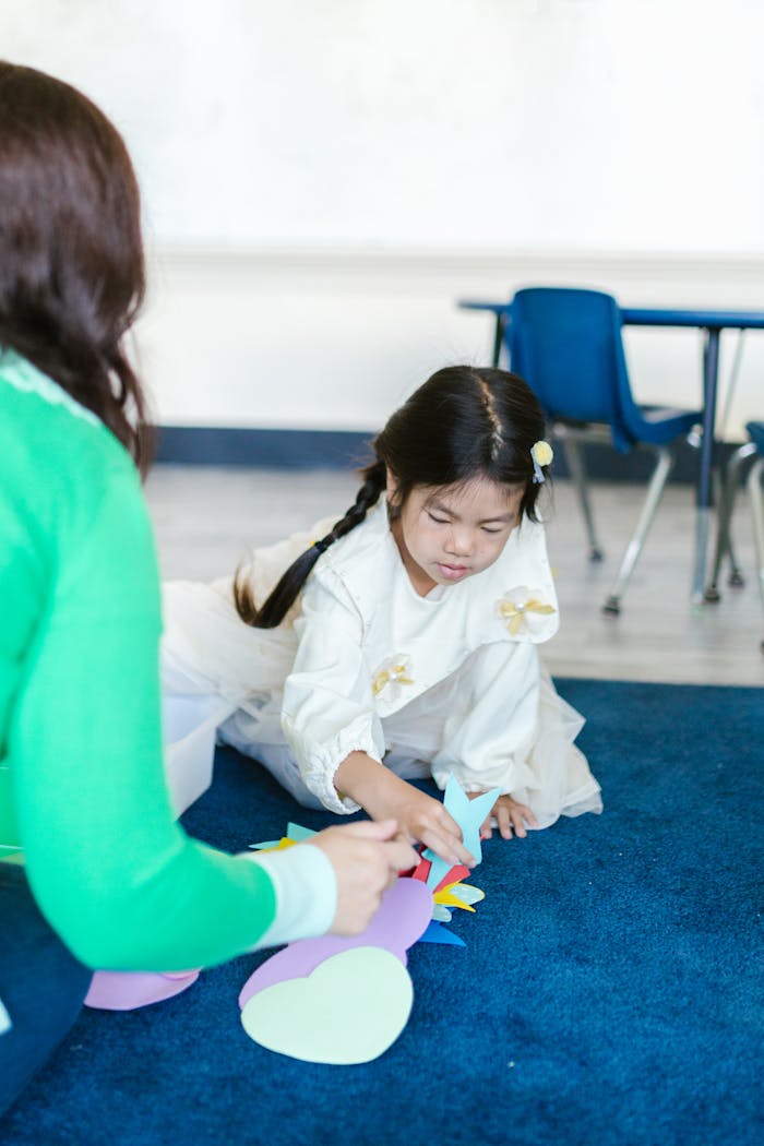 Young girl in a classroom setting participating in a fun educational activity with colorful cutouts.